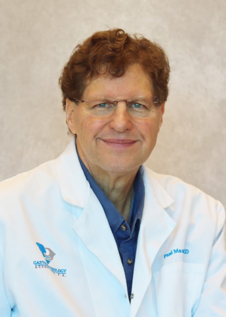 Dr. Paul Maz in a white coat with "Paul Maz MD" embroidered, smiling against a neutral background.